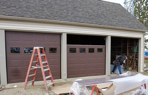 A house with an open garage door and a ladder inside, indicating ongoing work.