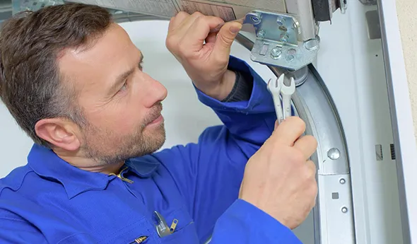 A technician in a blue uniform working on a garage door, highlighting repair expertise.