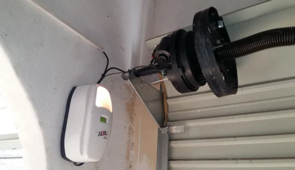 A technician installing a garage door motor, with text about electric garage door motor repair services in San Marcos, TX.