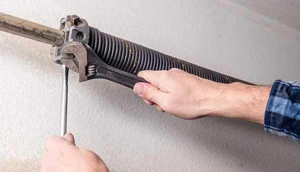A technician adjusting a garage door cable with a tool in San Antonio, TX
