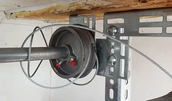 Close-up of a garage door mechanism with visible cables and a spring in Boerne, TX.