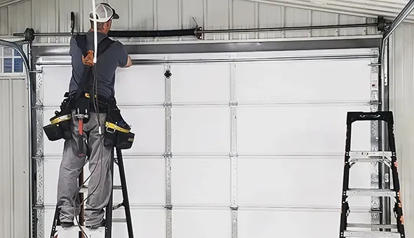 A worker on a ladder installing or repairing a garage door.