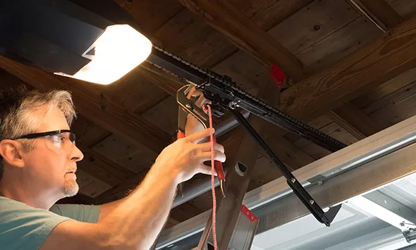 Professional garage door opener installation in San Antonio, TX, showing a technician working on a garage door with tools and equipment.